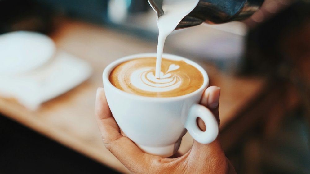 Susu dituang ke cangkir sampai terbentuk latte art