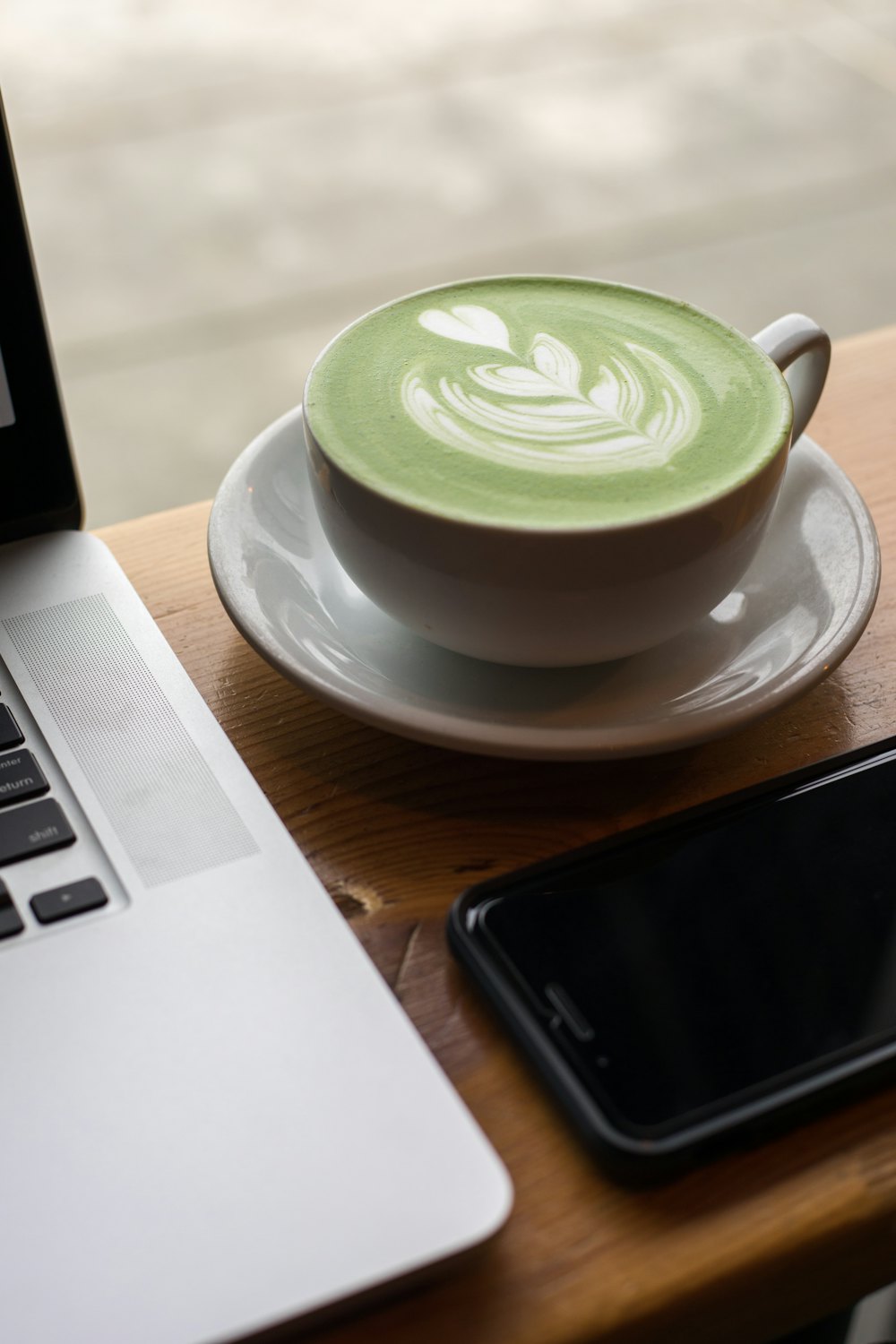 Matcha latte di meja kayu, di samping laptop